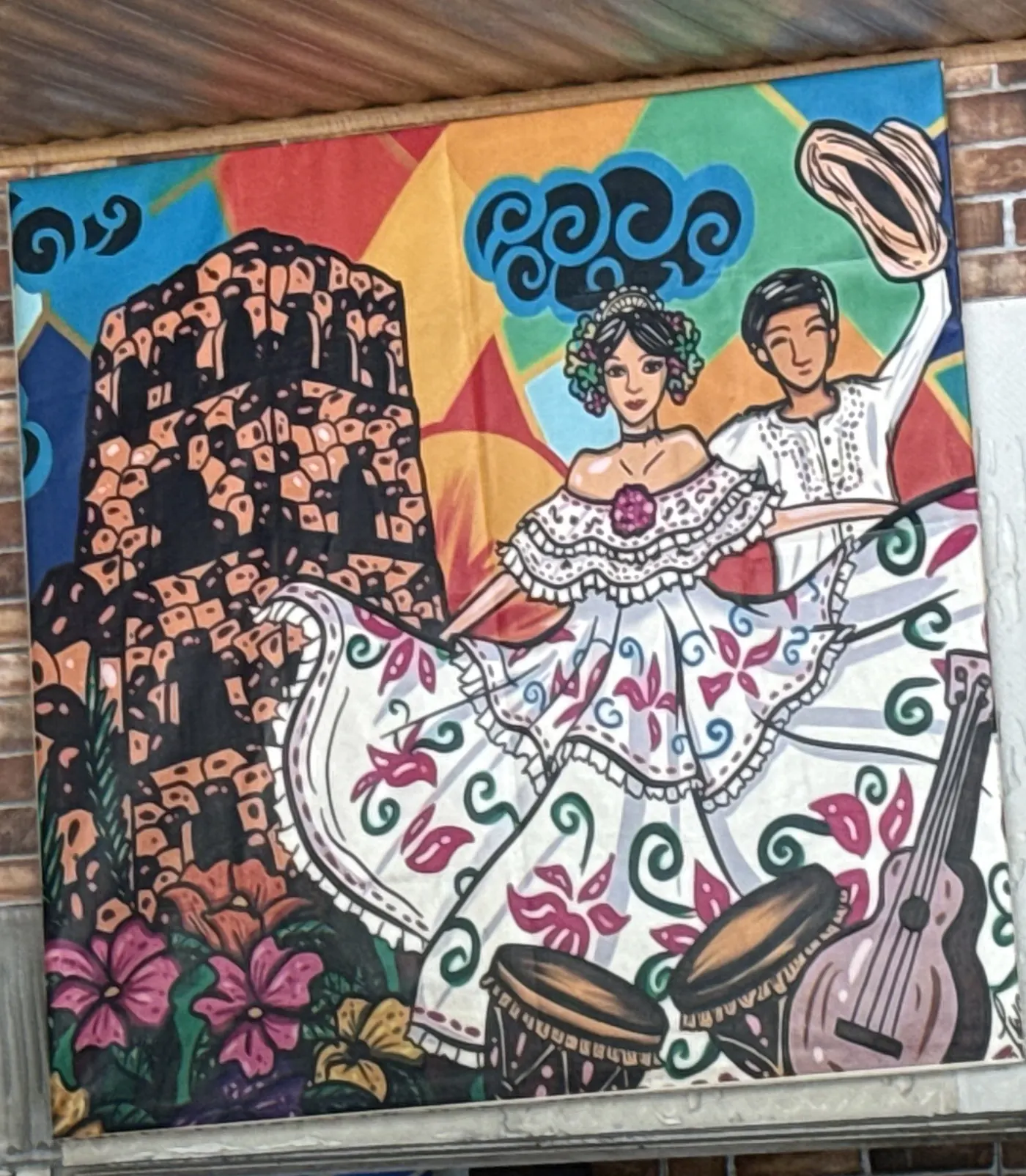Cuadro pintado en la pared del rancho: una pareja bailando tamborito, ella con pollera blanca bordada y tembleques en el pelo, él con camisilla y el sombrero en alto, con tambores y una mejorana pintados al pie